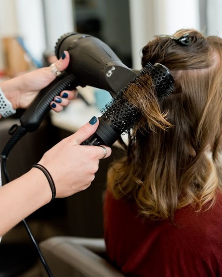 Stylist blow-drying a client's hair in the salon